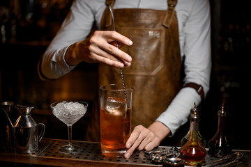 Bartender stirs alcohol drink with a spoon