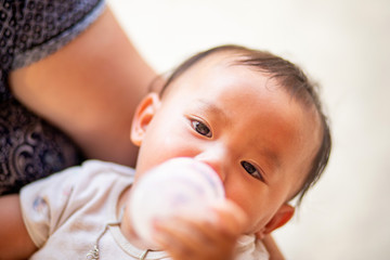 Asian baby girl sucking milk from bottle, Kid drinking milk