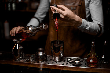 Fototapeta na wymiar Close shot of bartender pouring alcohol from jigger to shaker