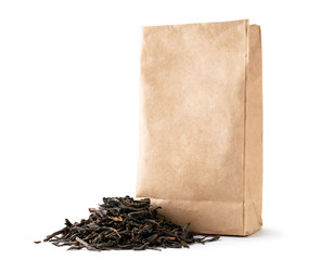 A pile of leaf tea near a paper pack on a white, isolated.