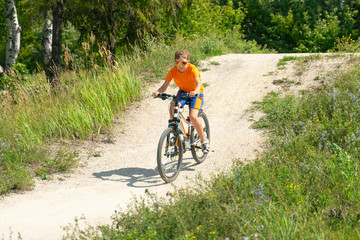 A boy on a mountain bike drives off a hill