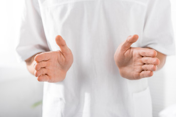 cropped view of masseur gesturing at camera in clinic