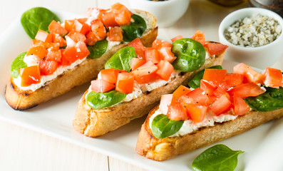 Tomato and cheese fresh made bruschetta. Italian tapas, antipasti with vegetables, herbs and oil on grilled ciabatta and baguette bread. Sandwich.