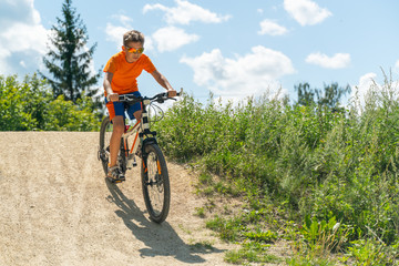 Fototapeta na wymiar A boy on a mountain bike drives off a hill