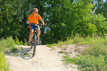 Naklejka premium Teenager riding a bike in the forest