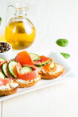 Salmon, cucumber and cream cheese bruschetta. Italian tapas, antipasti with vegetables, herbs and oil on grilled ciabatta and baguette bread. Sandwich.