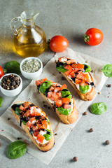 Tomato and cheese fresh made bruschetta. Italian tapas, antipasti with vegetables, herbs and oil on grilled ciabatta and baguette bread. Sandwich.