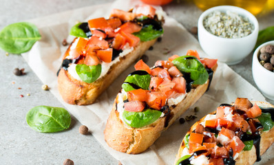 Tomato and cheese fresh made bruschetta. Italian tapas, antipasti with vegetables, herbs and oil on grilled ciabatta and baguette bread. Sandwich.