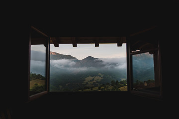 A cloudy, mountain sunrise viewed through a window in Asturias, Spain during summer. 