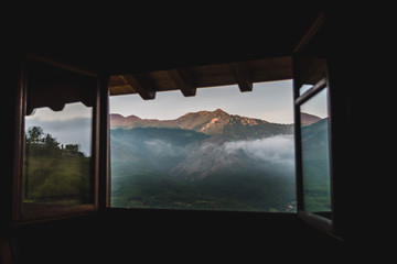 A cloudy, mountain sunrise viewed through a window in Asturias, Spain during summer. 