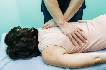 Chiropractor making treatment procedures. Young woman relaxing on massaging table, masseur working with her back. Beauty, health, rest, spa, body concept