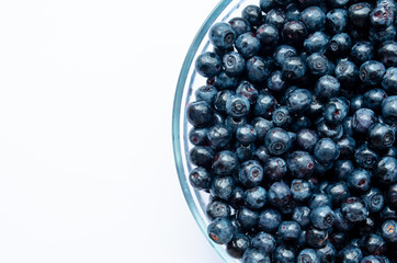  close-up of blueberries with leaves in a plate on a white background