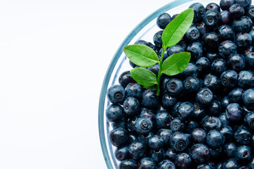  close-up of blueberries with leaves in a plate on a white background