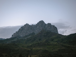 Fototapeta na wymiar Rocky mountain with green hills at the bottom