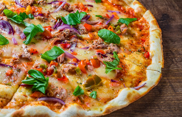 Pizza with Mozzarella cheese, onion,  tuna fish, tomato sauce, pepper, basil. Italian pizza on wooden table background