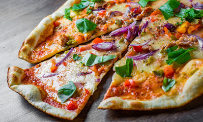 Pizza with Mozzarella cheese, onion,  tuna fish, tomato sauce, pepper, basil. Italian pizza on wooden table background