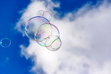Soap bubbles with their colors and transparencies floating in the blue sky