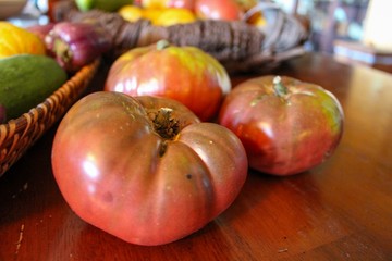 Closeup of Heirloom Tomatoes on Wooden Table and basket, selective focus