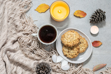 Hygge autumn composition with cup of aromatic tea, fresh sweet cookies, candles, warm blanket and decor.