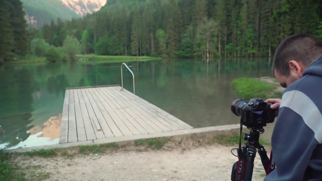 4k resolution video of a man taking photo using dslr camera of beautiful lake and mountain in the back