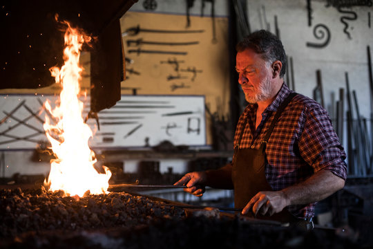 Blacksmith working at forge in his workshop