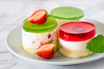 Mini round cold cheesecakes with fruit jelly and strawberries.