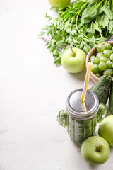 Green smoothie in a cactus shaped glass among the green ingredients of apples, spinach, avocado and parsley. Healthy raw food and detox concept. Copy space