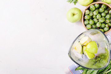 Ingredients for making healthy green smoothies made from apples, spinach, avocado and parsley around a blender glass bowl. Top view. flat lay, copy space