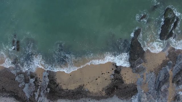 Aerial view of waves breaking on the shoreline of the Gower peninsula coast in Swansea, South Wales, UK