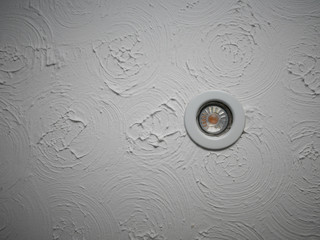LED downlight in swirly patterned ceiling plaster pattern known as Artex was common in the 80s.