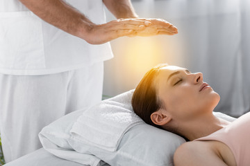 cropped view of healer standing near patient on massage table and cleaning aura - obrazy, fototapety, plakaty