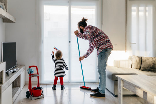 Father and little daughter cleaning the living room together - Powered by Adobe
