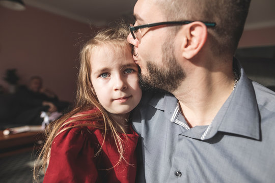 Father kissing daughter in sunshine at home
