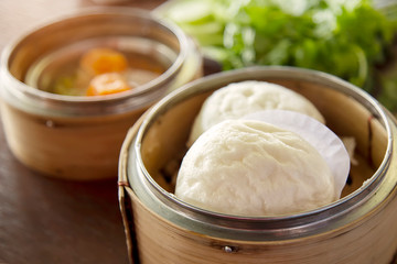 Steamed buns in a cup made of bamboo and vegetables on the table.Steamed food is a popular food in East Asia.