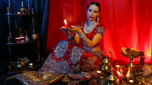 Beautiful young indian woman in traditional Sari clothing and Oriental Jewelry with candle