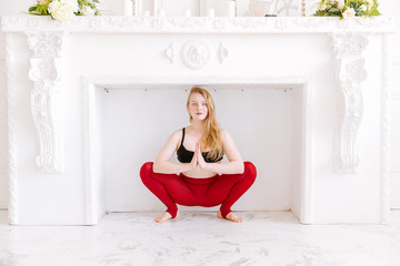 Yoga girl in red tights near the wall on a white background