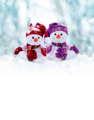 Two little snowmen the girl and the boy in caps and scarfs on snow in the winter. Background with a funny snowman. Christmas card. - obrazy, fototapety, plakaty