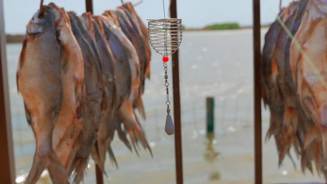 Feeder fishing gear on the background of dried fish hung in the sun. Pier near a small fishing village on the banks of the Volga River. 