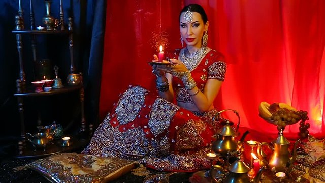 Beautiful young indian woman in traditional Sari clothing and Oriental Jewelry with candle