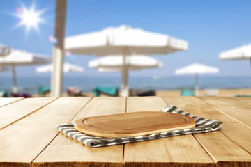 Table background with beautiful blue ocean and sandy beach view. Sun beds, umbrellas and the sea in...