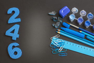 Education or back to school concept. Blue school supplies on blackboard with copy space.