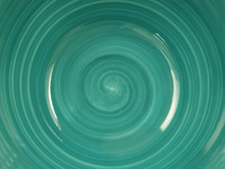  the bottom of a turquoise ceramic plate with a spiral pattern