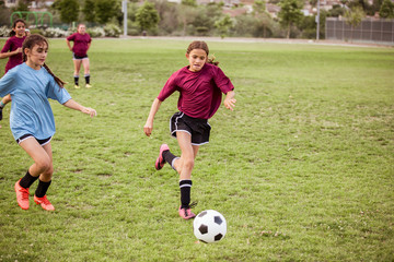 Full length of sporty girls running while playing soccer on field during competition © Cavan for Adobe