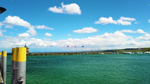 4K video of flying flags in the port. There is flag of European Union and Switzerland It is the city Constance on the Lake Constance, Bodensee. In the background is big snowy mountains Alps.