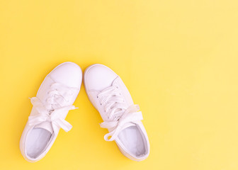 Pair of white sneakers on color background, top view