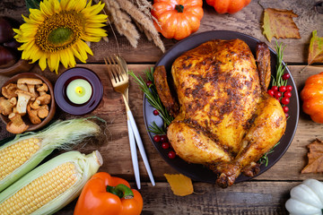 Happy thanksgiving background. Roasted whole chicken or turkey with autumn vegetables for thanksgiving dinner on wooden table. Thanksgiving Day concept. Top view