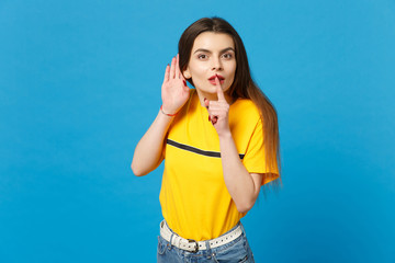 Amazed young woman in vivid casual clothes saying hush be quiet with finger on lips shhh gesture,...