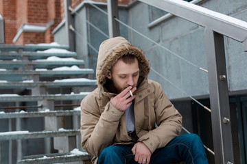 A bearded young man smokes a cigarette in winter