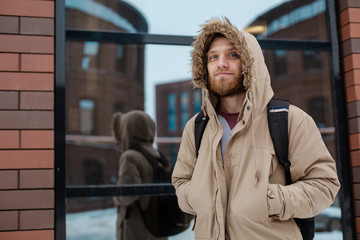 A bearded young man walks on winter street