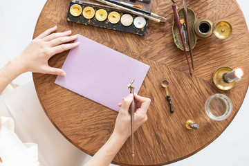 A copywriter writes a story. A hand is holding a ink pen in front of a blank sheet. Free space for...